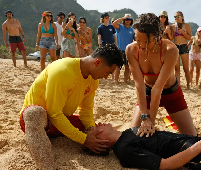 Lifeguards performing CPR on the beach during a rescue in Rescue: Hi-Surf, with Em's watch visible on her wrist