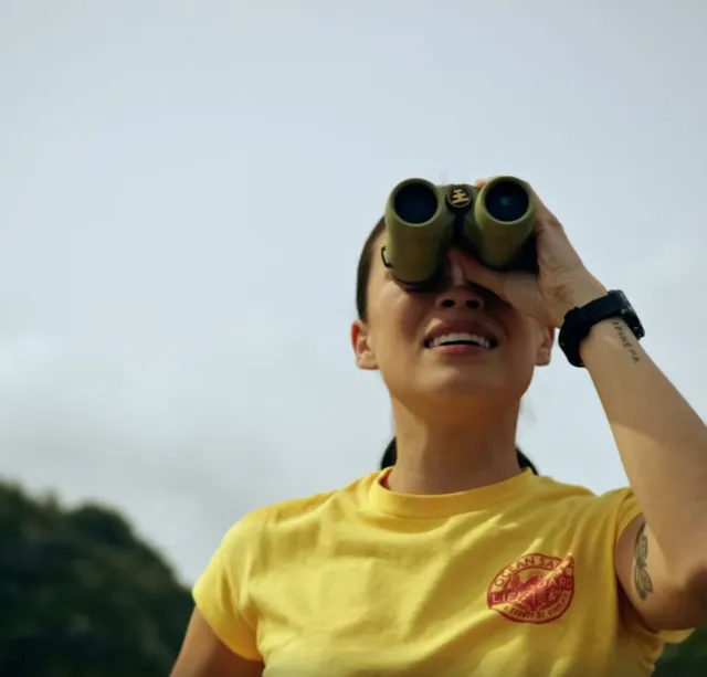 Hina scanning the water through binoculars as land eyes during a rescue in Rescue: Hi-Surf