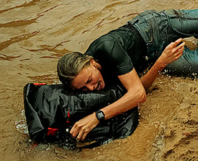Sasha clutching the Red Equipment backpack while crawling through muddy water in Apex